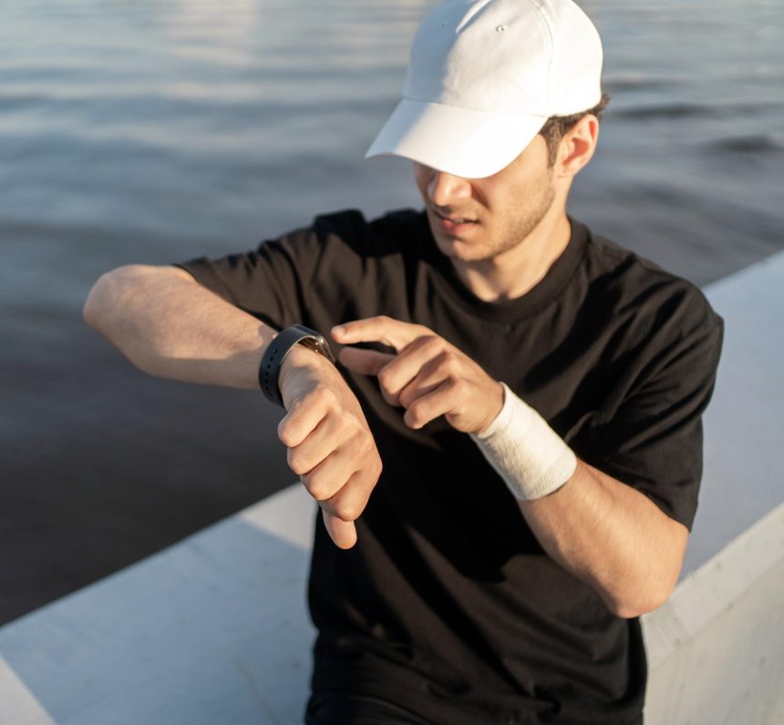 Patrzy na wyniki w aplikacji fitness Watch, sportowiec trenujący w mieście w odzieży sportowej