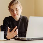 Kobieta używa laptop i telefon komórkowego dla jego dalekiej pracy w domu