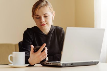Kobieta używa laptop i telefon komórkowego dla jego dalekiej pracy w domu