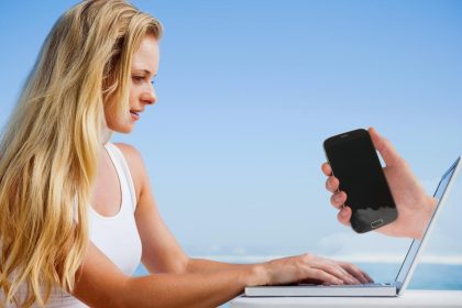 Złożony obraz ładnej blondynki używającej laptopa na plaży z telefonem trzymającym rękę