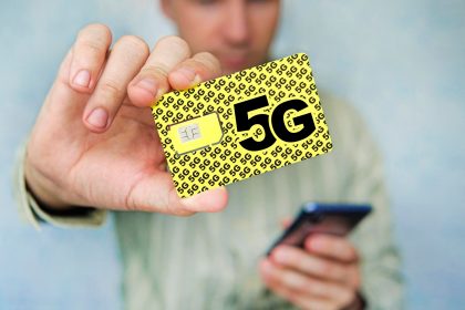 Mężczyzna trzyma żółtą kartę sim z napisem g i telefon komórkowy w ręku zastępując kartę sim