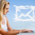 Złożony obraz ładnej blondynki używającej swojego laptopa na plaży przeciwko chmurowej wiadomości e-mail