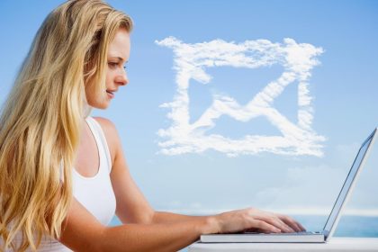 Złożony obraz ładnej blondynki używającej swojego laptopa na plaży przeciwko chmurowej wiadomości e-mail