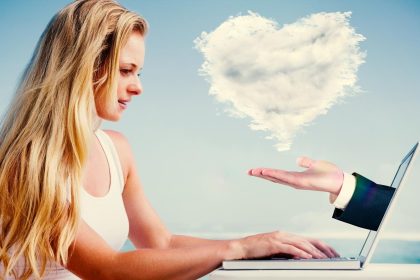 Złożony obraz ładnej blondynki używającej laptopa na plaży z ręką przedstawiającą obłoczne serce