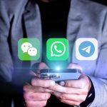 Mężczyzna trzyma komórkę z zieloną ikoną z napisem "Messenger"