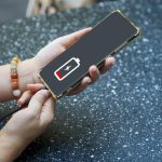 Zbliżenie rąk kobiety ładującej telefon komórkowy z ikoną ładowania