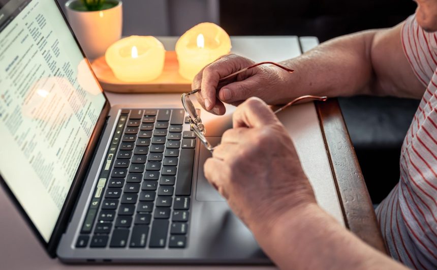 Stara kobieta czyta wiadomość na ręce zbliżenia laptopa