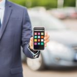 transport, podróż służbowa, koncepcja multimediów, technologii i ludzi - zbliżenie człowieka pokazującego ikony menu ekran smartfona na parkingu