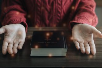 Zbliżenie otwartej Biblii z krzyżem na poranne nabożeństwo na drewnianym stole