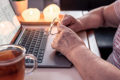 Emerytowana kobieta używa rąk laptopa z bliska