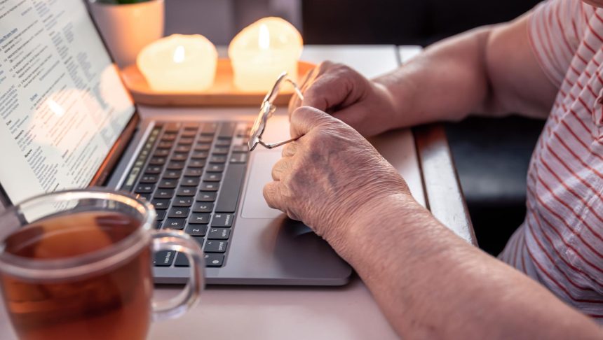 Emerytowana kobieta używa rąk laptopa z bliska