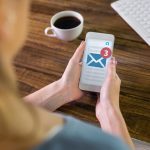 Kobieta używająca smartfona przed trzema otrzymanymi wiadomościami tekstowymi