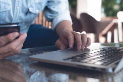 Niezwykły biznesmen pracujący na laptopie, korzystający z telefonu komórkowego, surfujący po Internecie w kawiarni