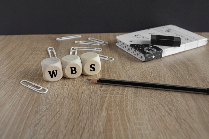 Akronim WBS Work Breakdown Struktura na drewnianych kostkach Piękny drewniany stół czarne tło Ołówek notatnik klipki do papieru Koncepcja biznesowa