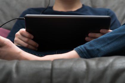Cyfrowy komputer typu tablet w męskich rękach od dołu widok zbliżenie Facet siedzący na kanapie gra w gry wideo na podręcznym gadżecie