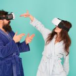 Ręce do góry Wstań i dostarczaj technologię VR i przyszłą komunikację VR Ekscytujące wrażenia Para w szlafroku nosi okulary VR Gry i rozrywka Mężczyzna i kobieta odkrywają VR w domu