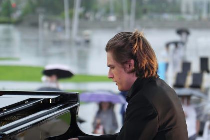 Utalentowany pianista występuje na wydarzeniu na świeżym powietrzu, podczas gdy odważni uczestnicy cieszą się deszczową pogodą.