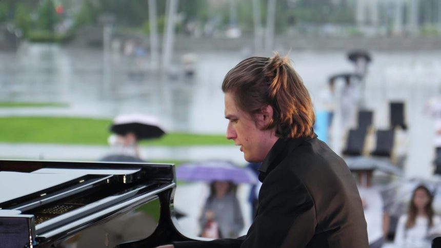 Utalentowany pianista występuje na wydarzeniu na świeżym powietrzu, podczas gdy odważni uczestnicy cieszą się deszczową pogodą.
