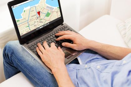technologia, lokalizacja, nawigacja, koncepcja ludzi i stylu życia - zbliżenie męskich rąk piszących na laptopie z mapą nawigatora gps na ekranie w domu
