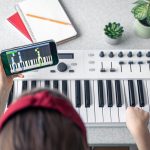 Mała dziewczynka uczy się grać na pianinie dzięki lekcji muzyki online na smartfonie