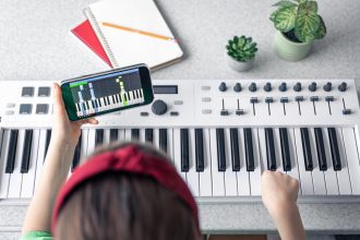 Mała dziewczynka uczy się grać na pianinie dzięki lekcji muzyki online na smartfonie