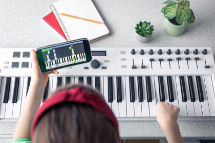 Mała dziewczynka uczy się grać na pianinie dzięki lekcji muzyki online na smartfonie