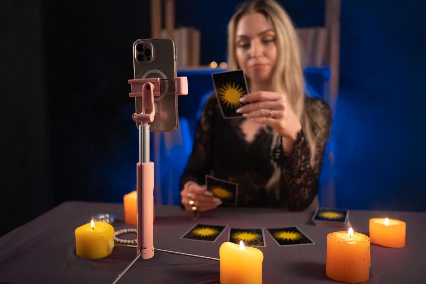 Astrologia online Wróżbiarz używa smartfona czyta karty tarota do przewidywań mówiąc klientom poprzez świadczenie usług za pośrednictwem telefonów komórkowych Koncepcja wróżbiarstwa ezoteryzmu