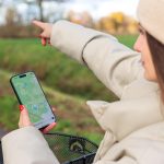 Kobieta smartfon map app nawigacja na świeżym powietrzu jazda na rowerze jesienne pole zielona trawa koszyk rowerowy