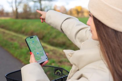 Kobieta smartfon map app nawigacja na świeżym powietrzu jazda na rowerze jesienne pole zielona trawa koszyk rowerowy