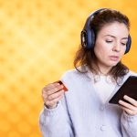 Kobieta trzymająca e-reader, słuchająca muzyki, kupująca książki.