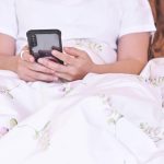 Kobieta korzystająca ze smartfona na łóżku Sprawdzanie wiadomości i przeglądanie informacji Koncepcja technologii