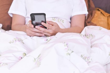 Kobieta korzystająca ze smartfona na łóżku Sprawdzanie wiadomości i przeglądanie informacji Koncepcja technologii