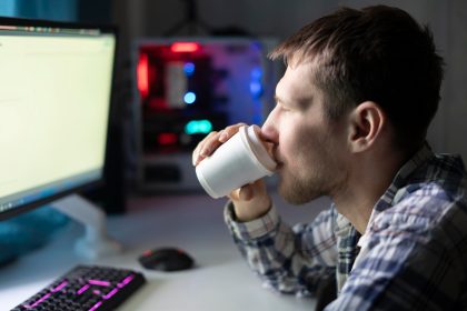 Pracownik biurowy trzymający papierowy kubek z gorącym napojem podczas wykonywania zadania