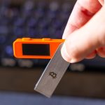Adult man holding bitcoin key and electronic device in office