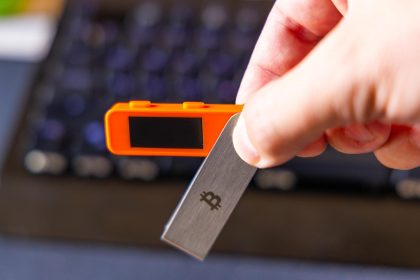 Adult man holding bitcoin key and electronic device in office