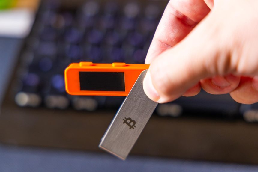Adult man holding bitcoin key and electronic device in office