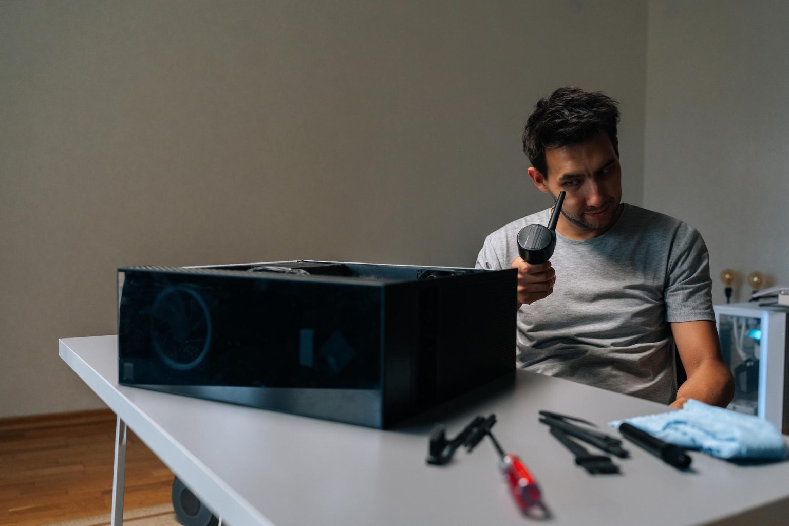 Young technician male examining small vacuum cleaner during cleaning computer parts ensuring optimal