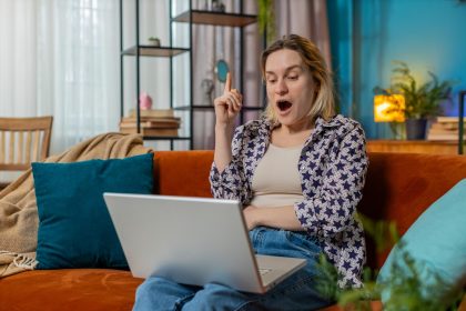 Myślliwa młoda kobieta freelancer miała pomysł i pisanie na laptopie netbook świętując zwycięstwo