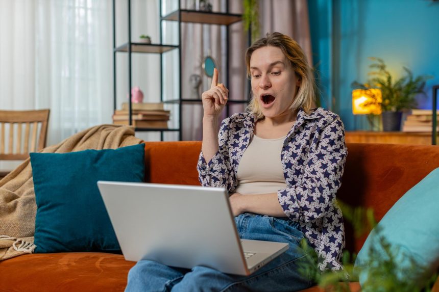 Myślliwa młoda kobieta freelancer miała pomysł i pisanie na laptopie netbook świętując zwycięstwo