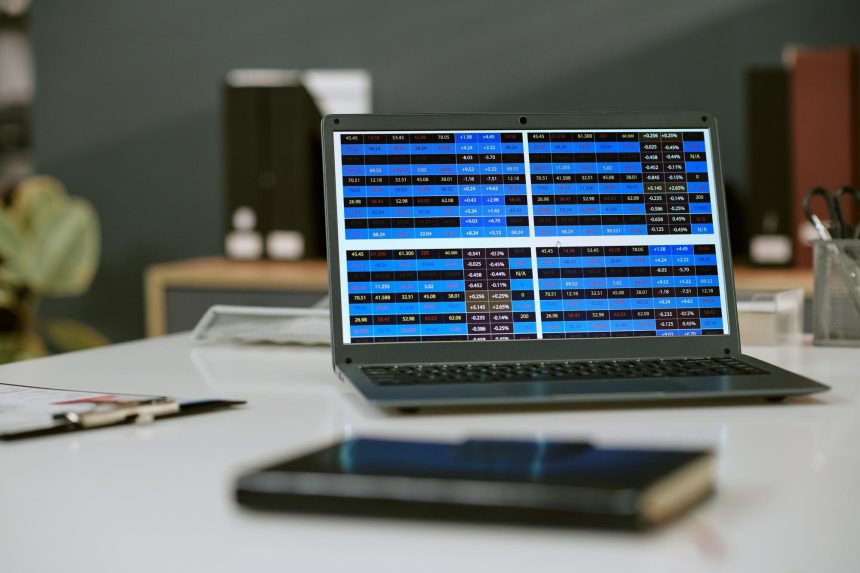 Laptop displaying financial data charts on office desk during workday