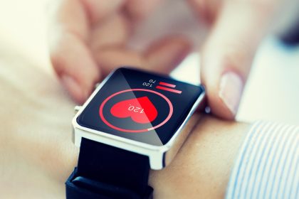 koncepcja technologii, opieki zdrowotnej i ludzi - zbliżenie rąk kobiety sprawdzających puls za pomocą smartwatcha z ikoną serca na ekranie