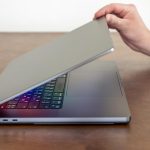 Ręka mężczyzny otwiera laptopa z wielokolorowym świecącym ekranem