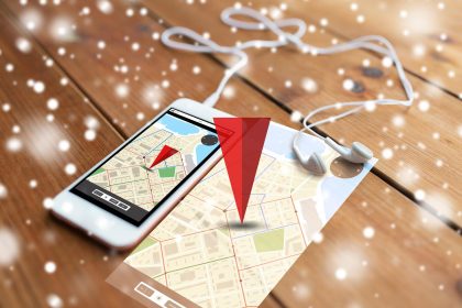 technologia, nawigacja, gadżet i koncepcja obiektu - zbliżenie białego smartfona i słuchawek na drewnianej powierzchni z mapą nawigatora GPS na ekranie