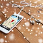 technologia, nawigacja, gadżet i koncepcja obiektu - zbliżenie białego smartfona i słuchawek na drewnianej powierzchni z mapą nawigatora GPS na ekranie