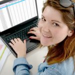 Ładna młoda biznesowa kobieta pracuje przy laptopem w biurze