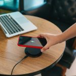 Ładowanie baterii telefonu komórkowego za pomocą urządzenia bezprzewodowego w stole Ładowanie smartfonu na poduszce ładującej Telefon komórkowy w pobliżu ładowarki bezprzewodowej