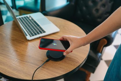 Ładowanie baterii telefonu komórkowego za pomocą urządzenia bezprzewodowego w stole Ładowanie smartfonu na poduszce ładującej Telefon komórkowy w pobliżu ładowarki bezprzewodowej
