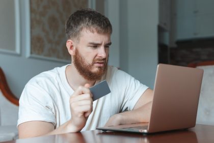 Nerwowy, smutny, zdezorientowany, młody człowiek, zestresowany, zaniepokojony, facet, który ma problemy z płaceniem za zakupy online.