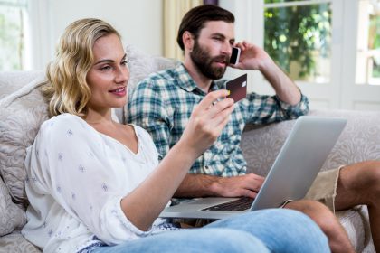 Kobiety mienia karta debetowa mężczyzna opowiada na telefonie z laptopem