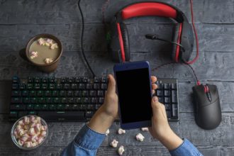 Dziewczyna trzyma telefon komórkowy na tle akcesoriów komputerowych, kawy i pianki
